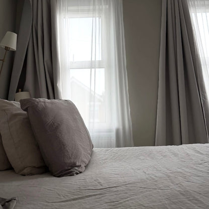 A neutrally styled bedroom setting, featuring elegant tulle wave curtains against a backdrop of sunshine.