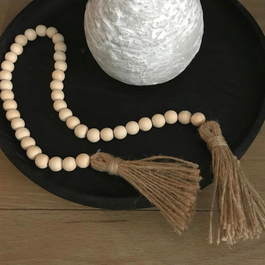 Wooden farmhouse beads decor, with a tassel on a dark surface