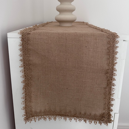Farmouse, jute table runner on a white surface with a decorative vase.