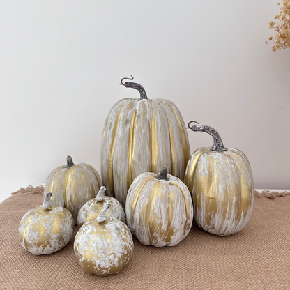 Decorative pumpkins with gold and white patterns on a textured surface