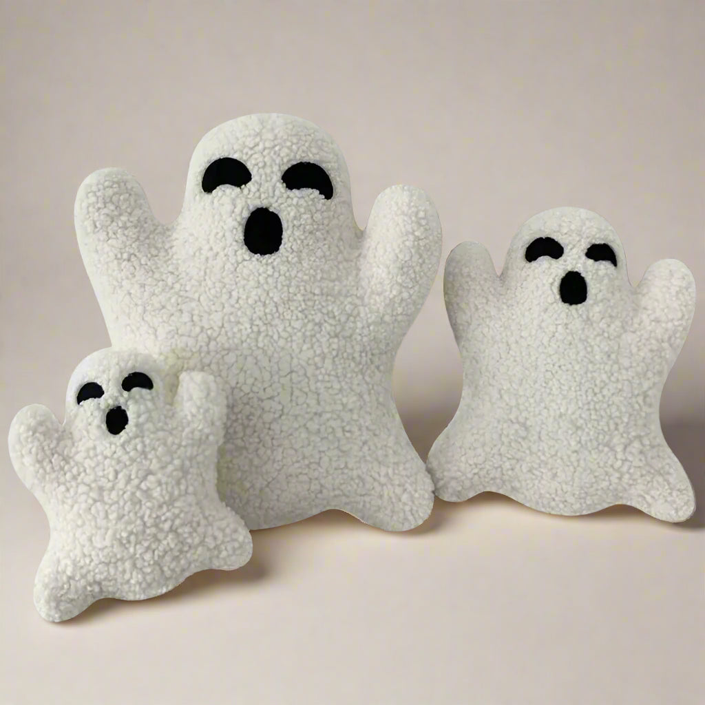 Three white ghost-shaped plush cushions on a white background
