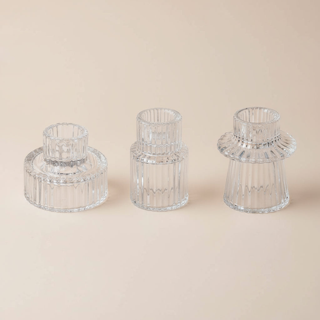 Three clear glass candle holders on a white background