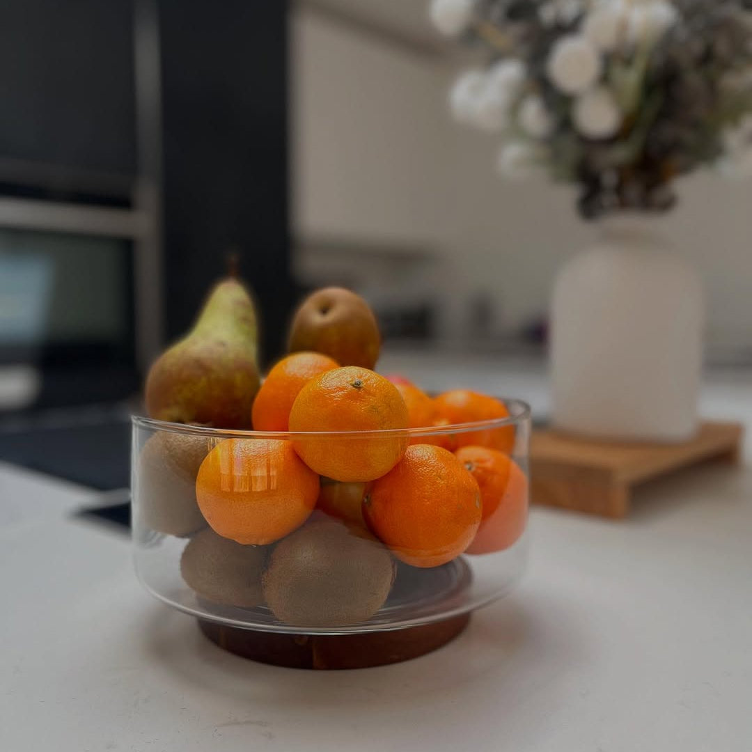 Clear glass bowl with oranges and pears on a blurred background