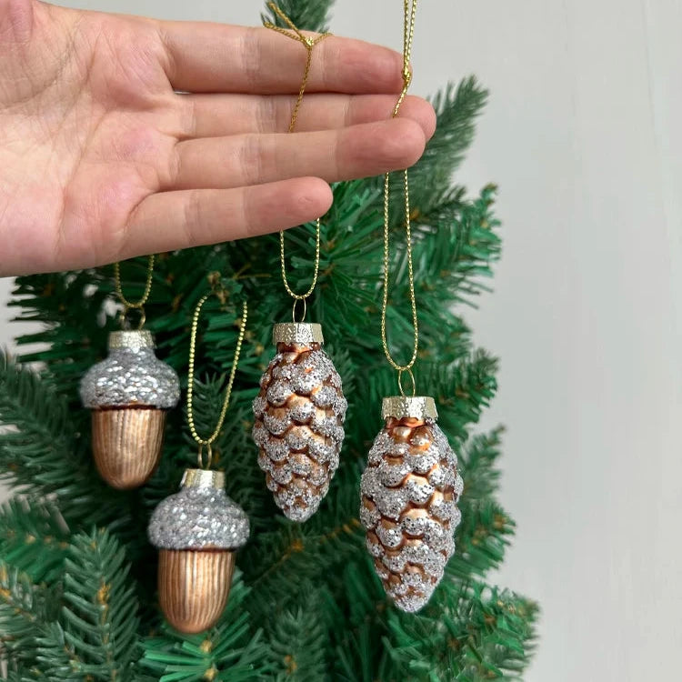 Glass pine cone and acorn ornaments with silver glitter. 4-piece set. Nature-inspired and elegant. Ideal for trees, wreaths, or festive accents. 