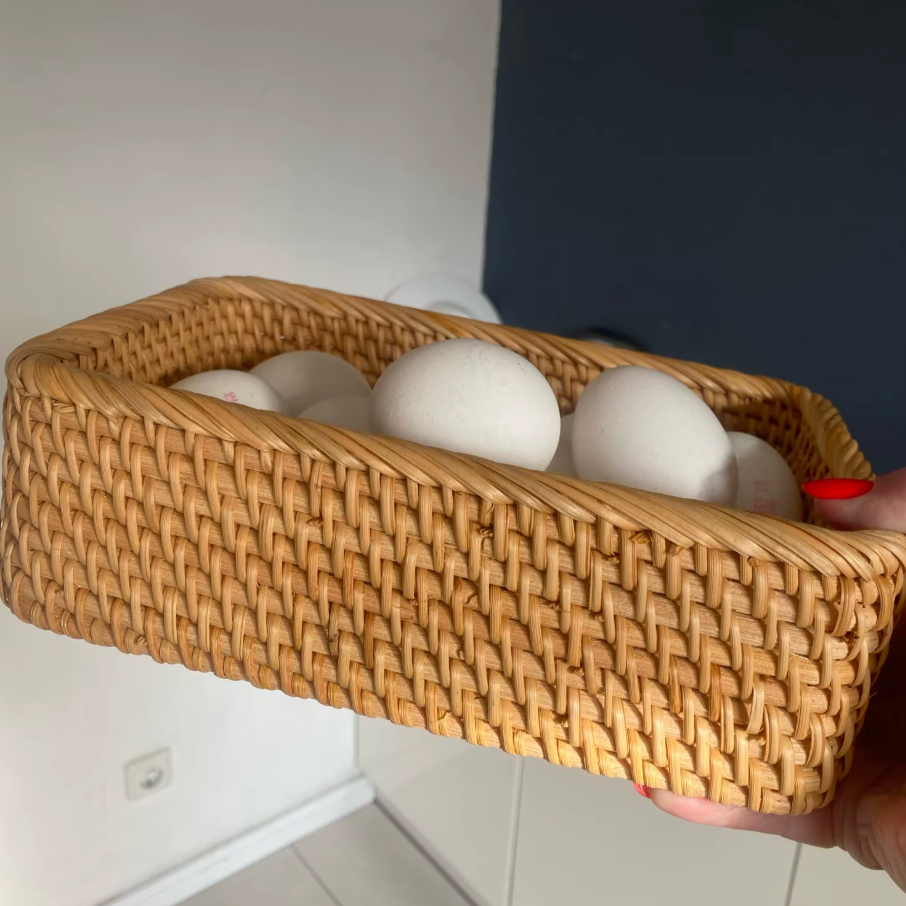 Woven basket with eggs held by a person against a neutral background