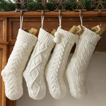 Four white cable-knitted Christmas stockings hanging from a wooden mantel, each with a festive design.