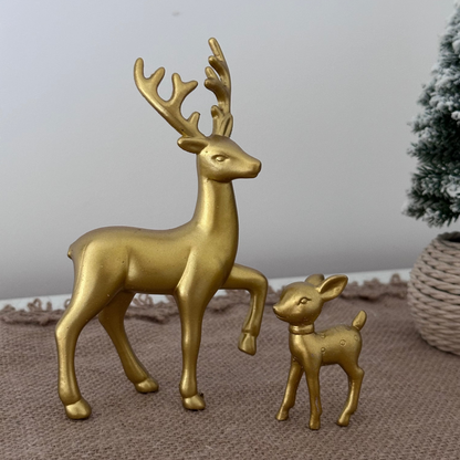 Gold deer figurines on a textured surface with a neutral background