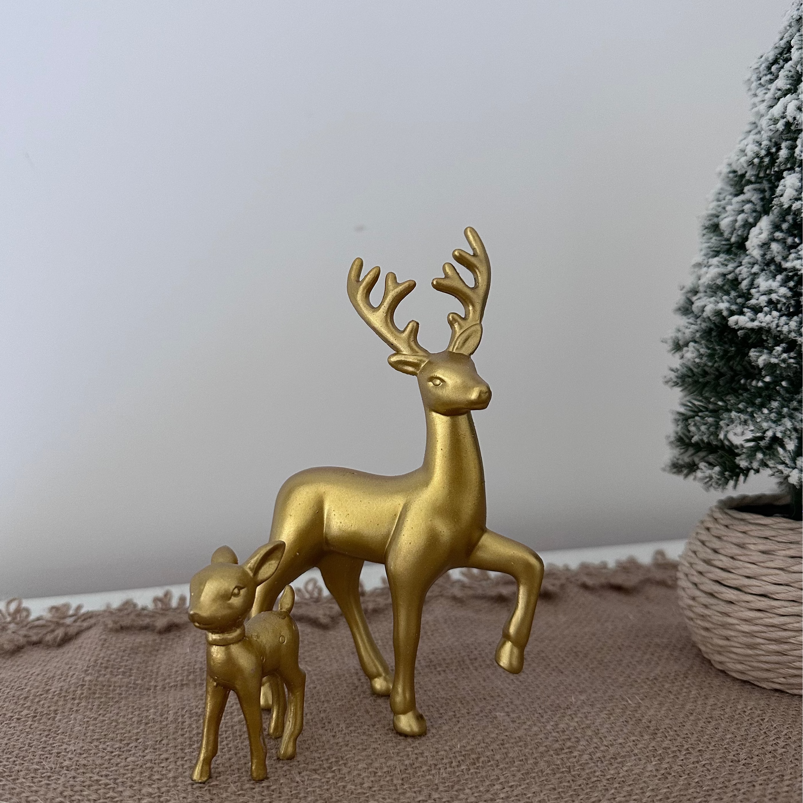 Gold deer figurines on a textured surface with a neutral background