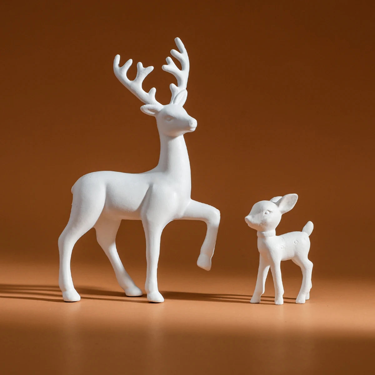 White deer figurine and fawn on a brown background