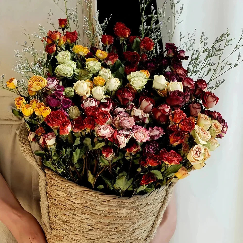 Bouquet of colorful, dried roses in a woven basket held by a person.