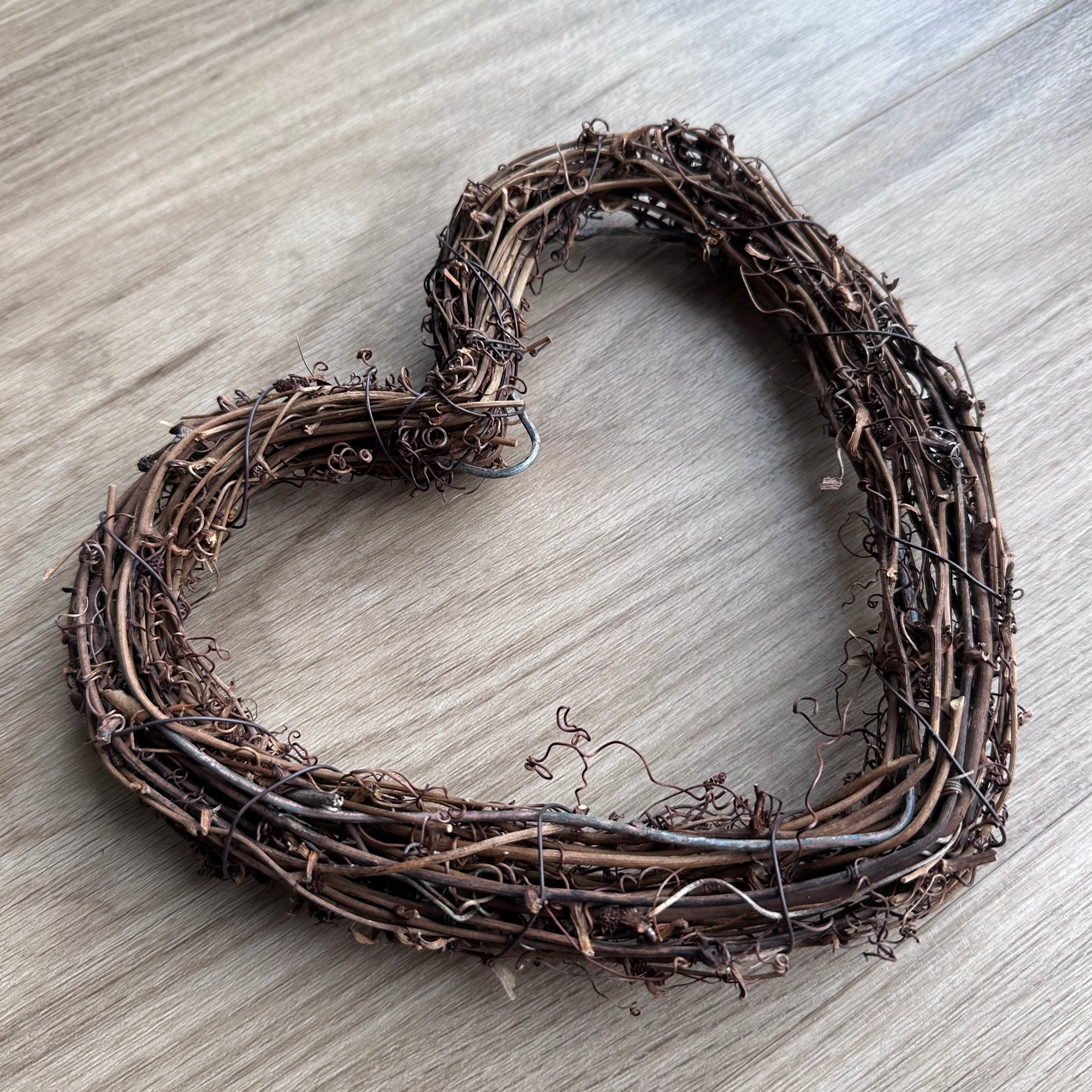 Heart-shaped wreath made of twigs on a wooden surface