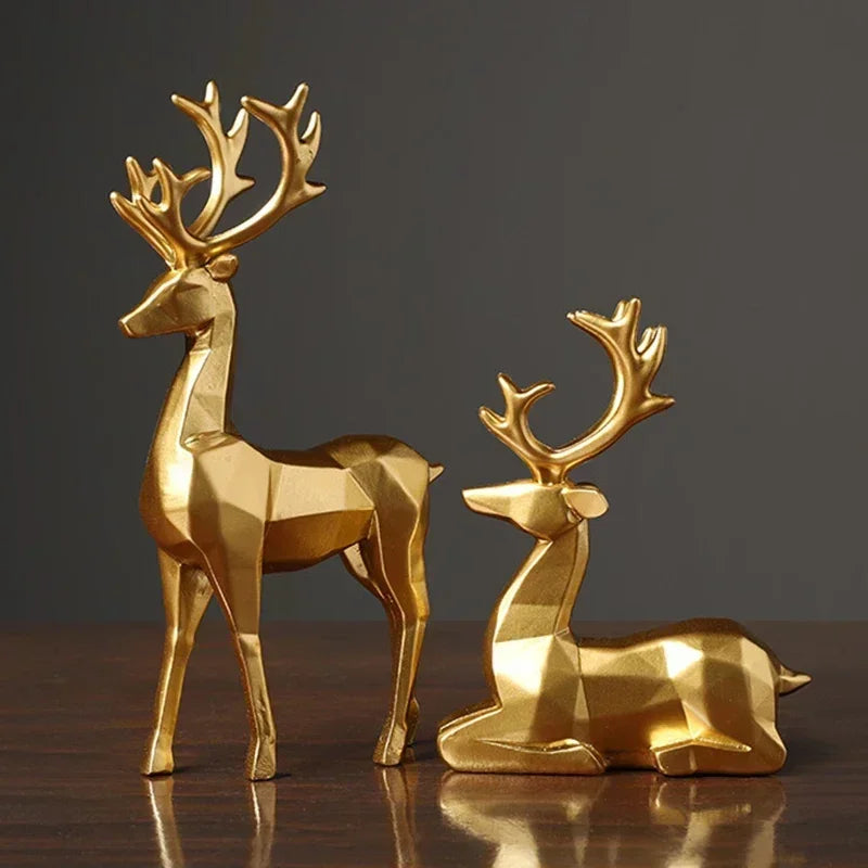A set of two golden, geometric reindeer ornaments placed on a wooden, glossy surface.