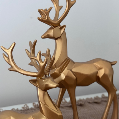 Gold deer figurines on a textured surface with a neutral background