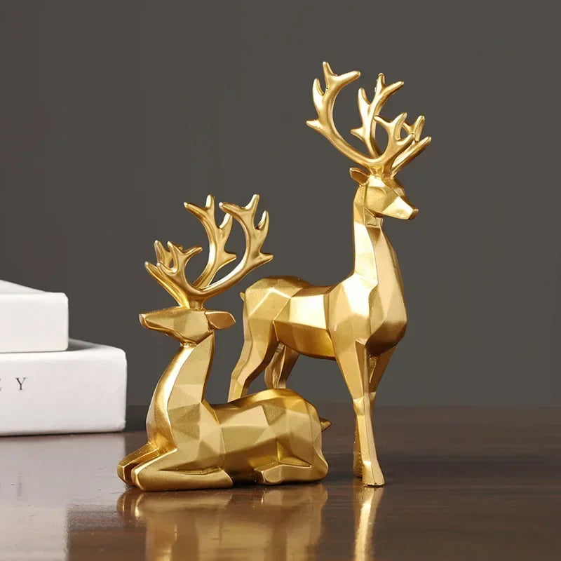 A set of two golden, geometric reindeer ornaments placed on a surface.