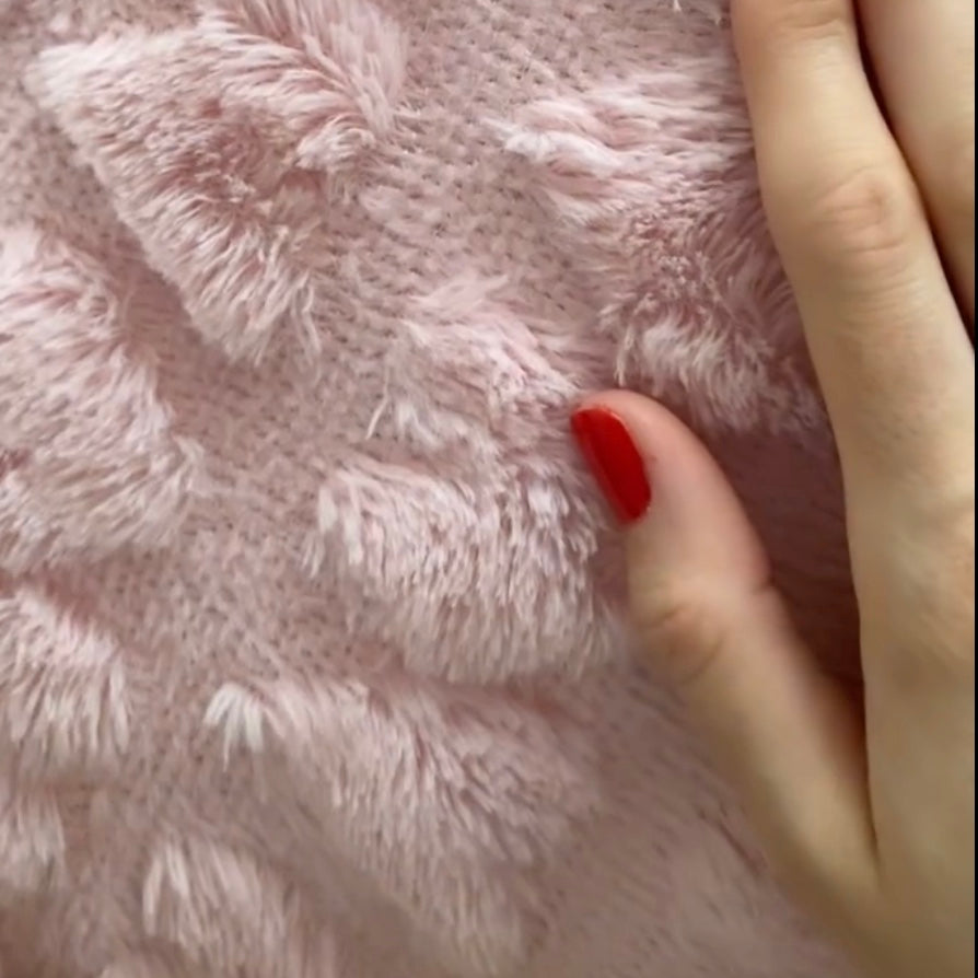 A close up image showing the rabbit soft texture of a plush heart pillow cover 