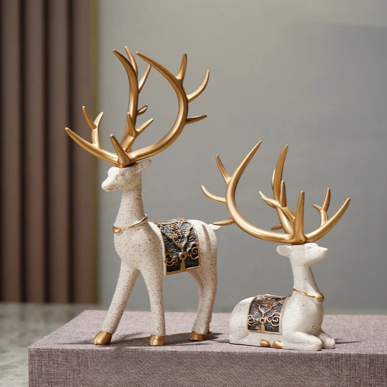 Decorative deer figurines with gold antlers on a gray surface.