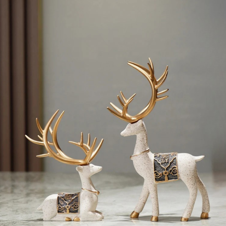 Decorative deer figurines with gold antlers on a neutral background