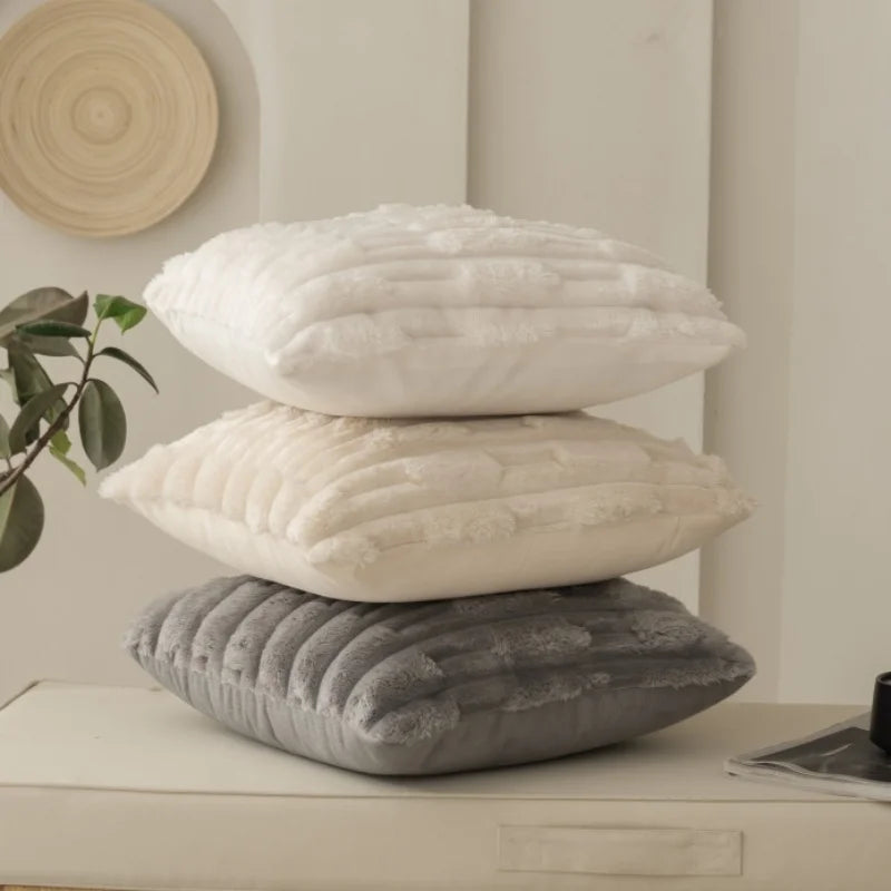 Stack of three textured pillows on a surface with a neutral background