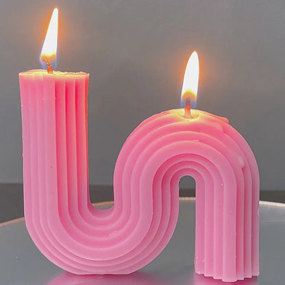 A decorative S-shaped candle made from soy wax in the colour dark pink