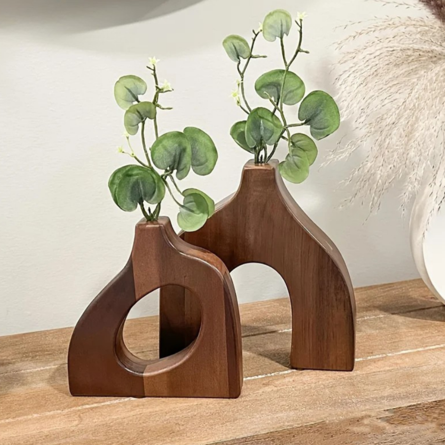 Two wooden vases with plant branches on a wooden surface