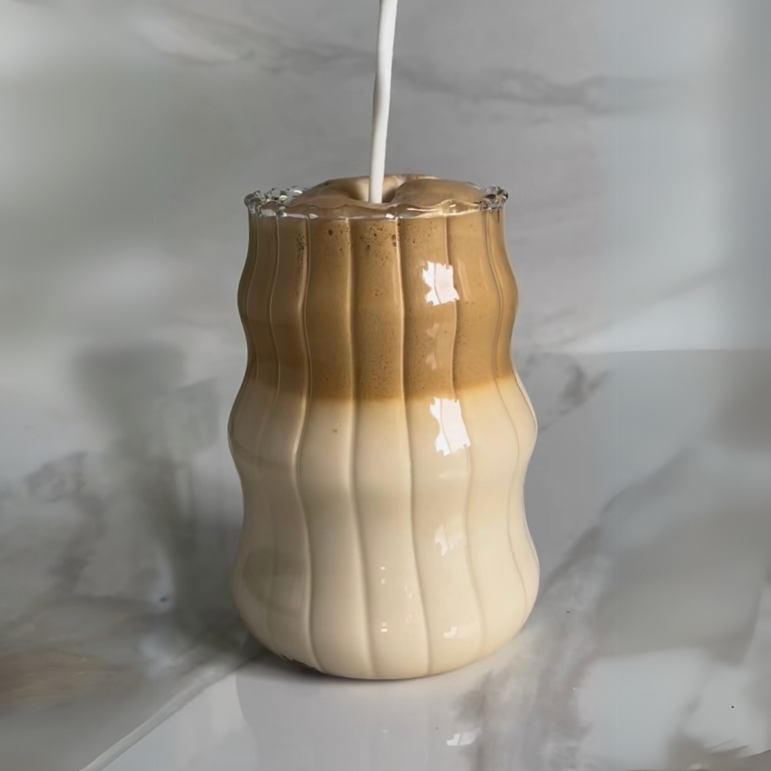 Wavy-patterned, striped retro glass with a liquid inside on a marble surface