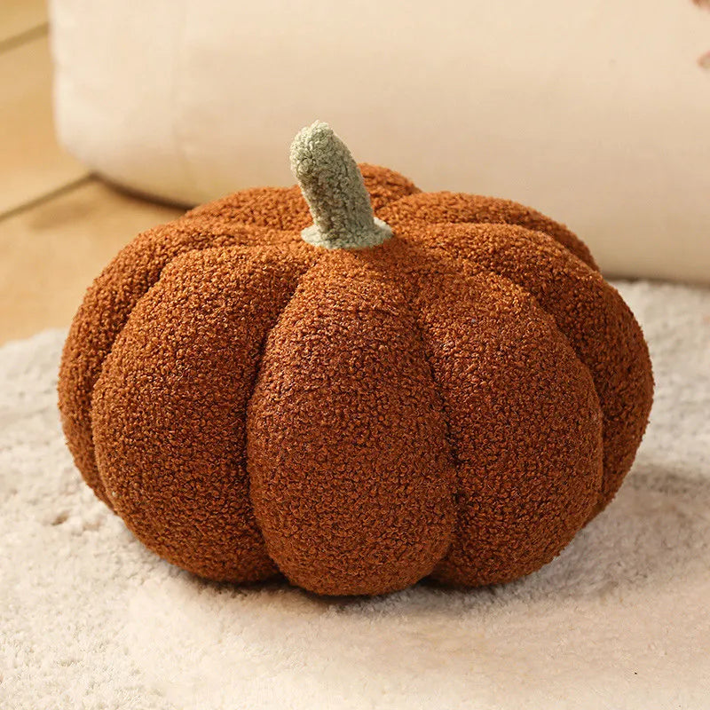Brown textured pumpkin cushion with a green stem on a beige blanket