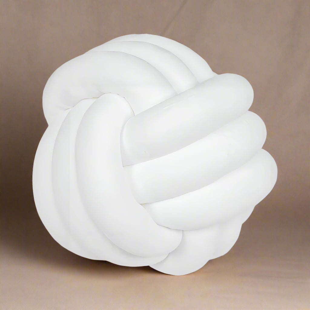A white knot-shaped cushion on a beige background