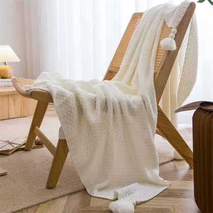 A white Nordic waffle blanket draped over a chair in a minimalist room setting. 