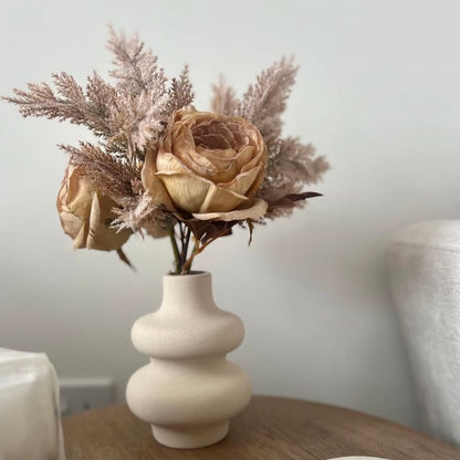 Wavy, white ceramic vase styled with dried flowers in a minimalist setting. 