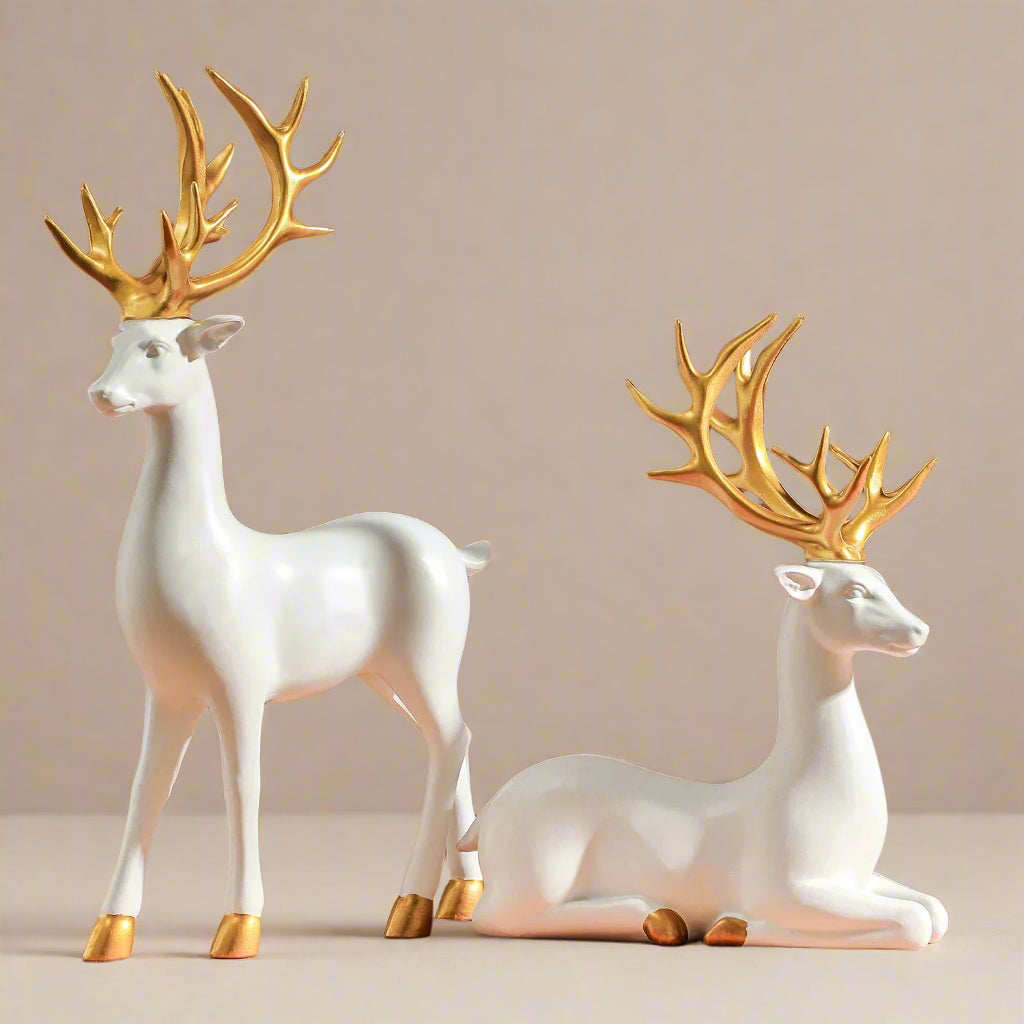 Two white, resin deer figurines with gold antlers on a brown background