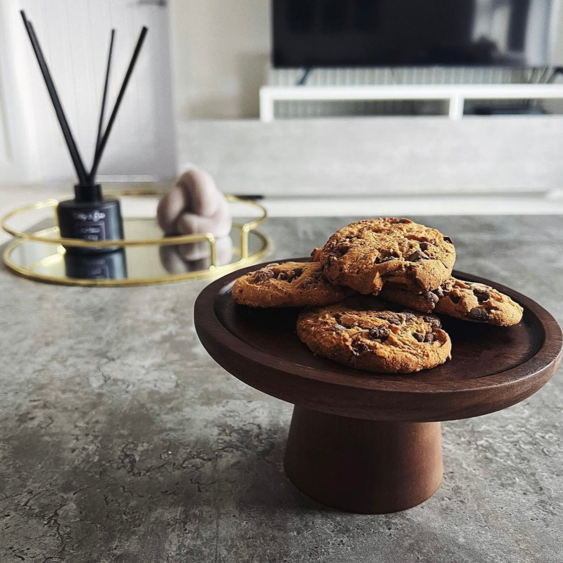 Natural wood cake stand presenting chocolate cookies. 
