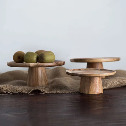 Two wooden cake stands of different sizes, the larger one is on a burlap fabric, with a white background behind them.